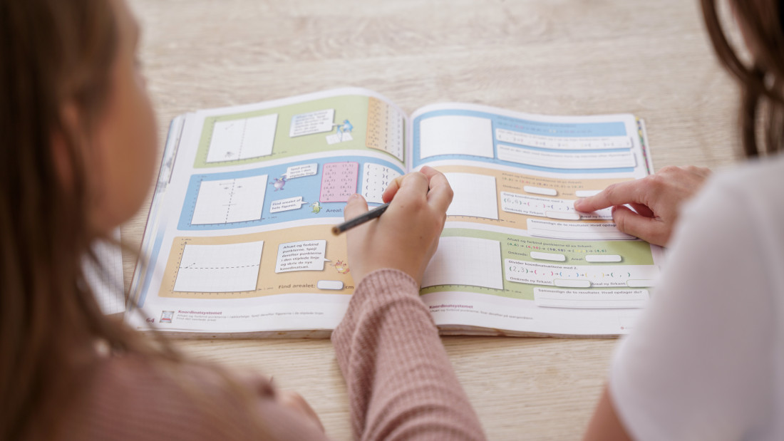 Mentor og mentee ser på oppgavene sammen til leksehjelp med MentorNorge