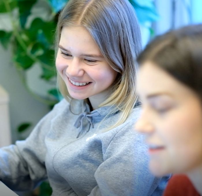 Elev Emma smiler mens hun ser på leksene sine med en privatunderviser/mentor fra MentorNorge